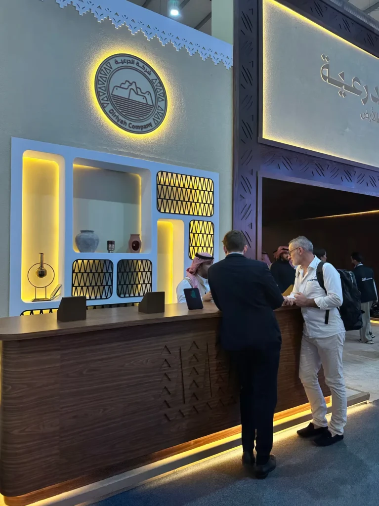 Visitors speaking at the illuminated Diriyah Company stand during Cityscape Global.