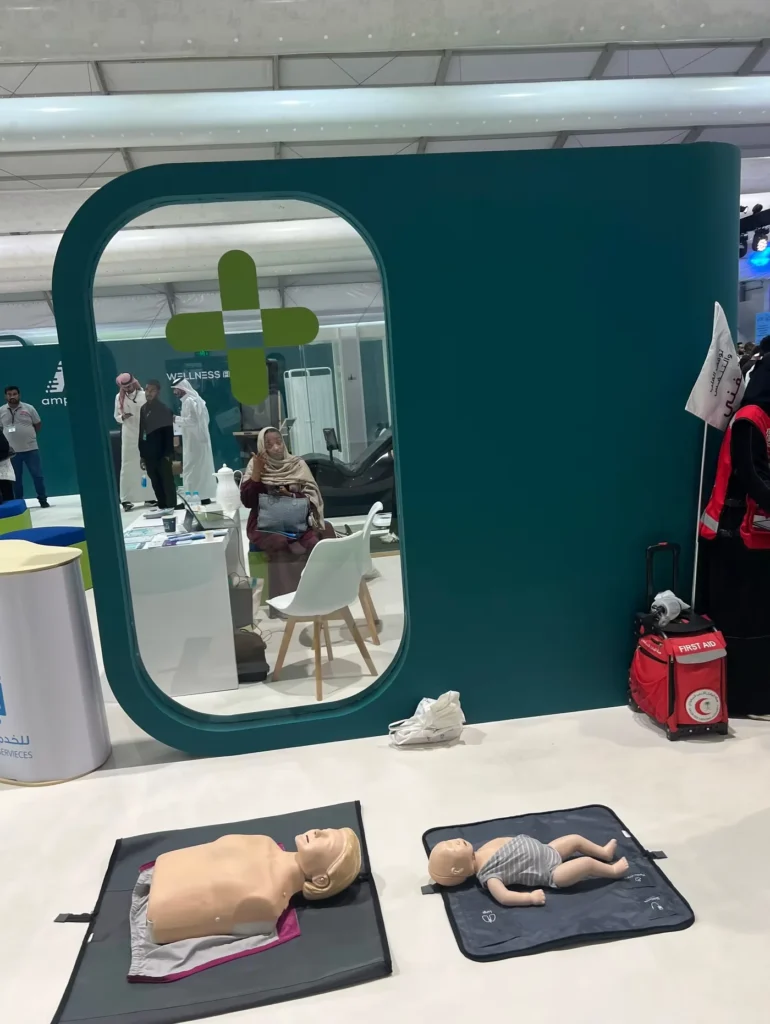 Adult and infant first aid training mannequins displayed at a healthcare exhibition stand.