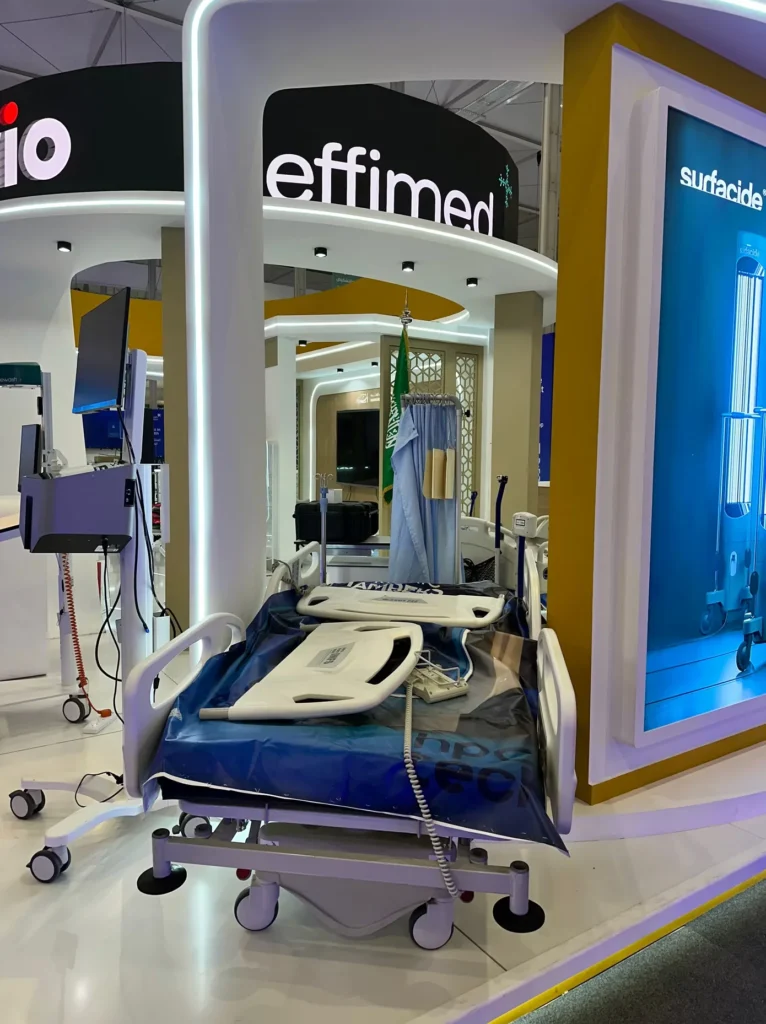 Hospital bed and patient care technology displayed at a medical exhibition stand.