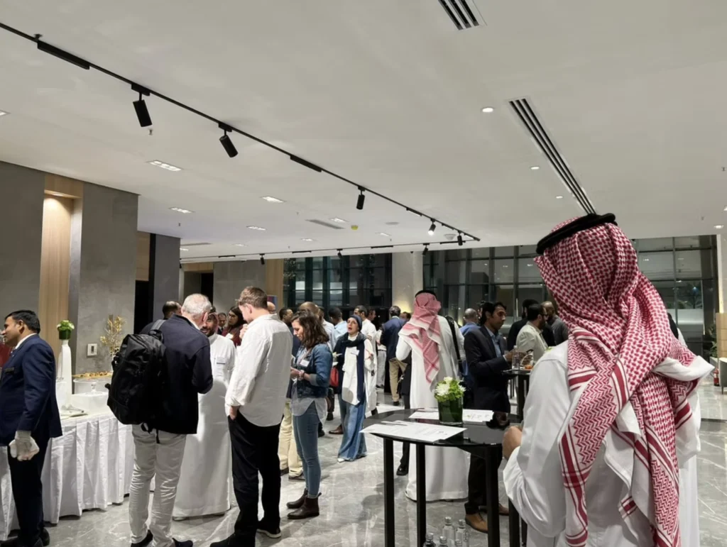 Saudi and international professionals networking at a business event in Saudi Arabia.