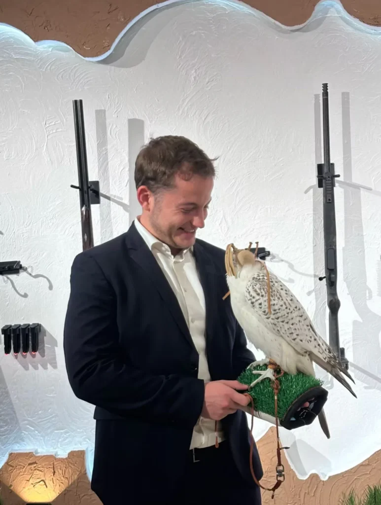International visitor holding a hooded white falcon at the exhibition.