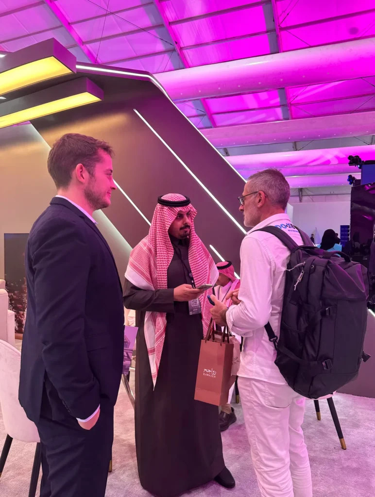 Business discussion between international visitors and a Saudi representative at the Ministry of Sport stand.