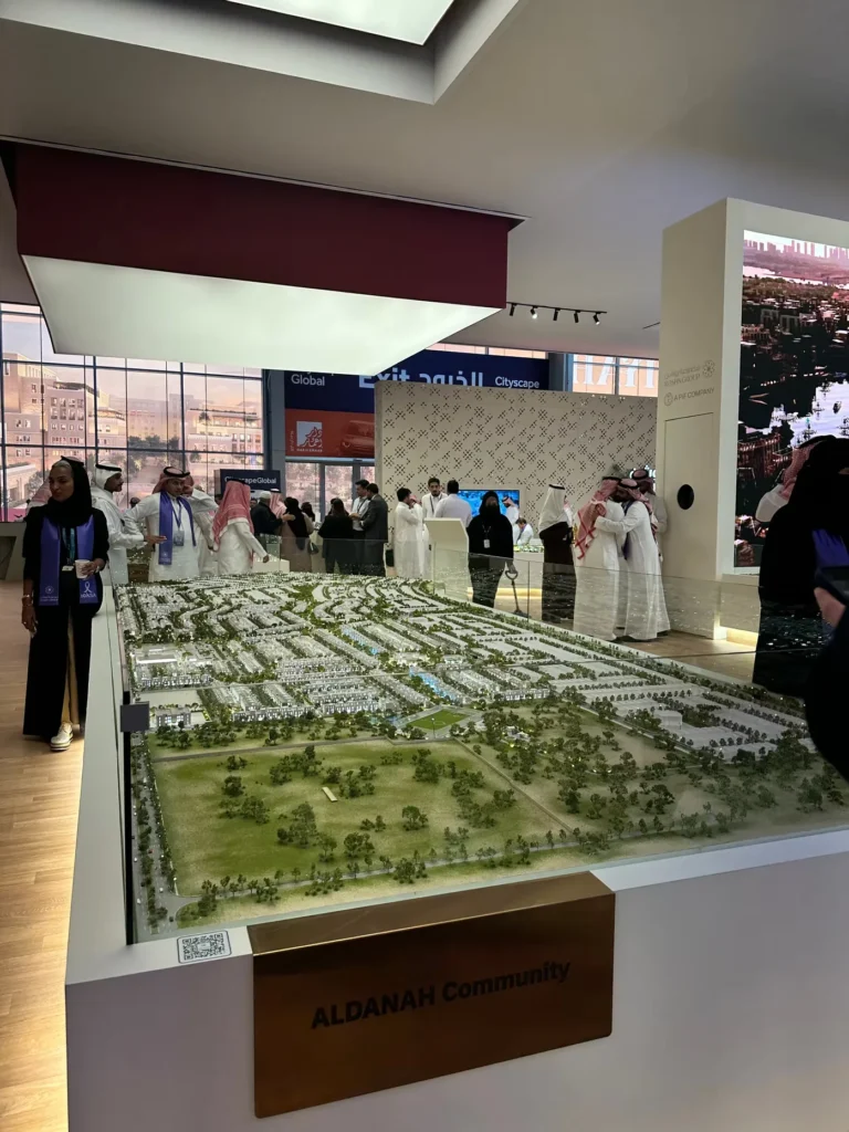 Visitors viewing a large ROSHN Group community master plan at Cityscape Global.