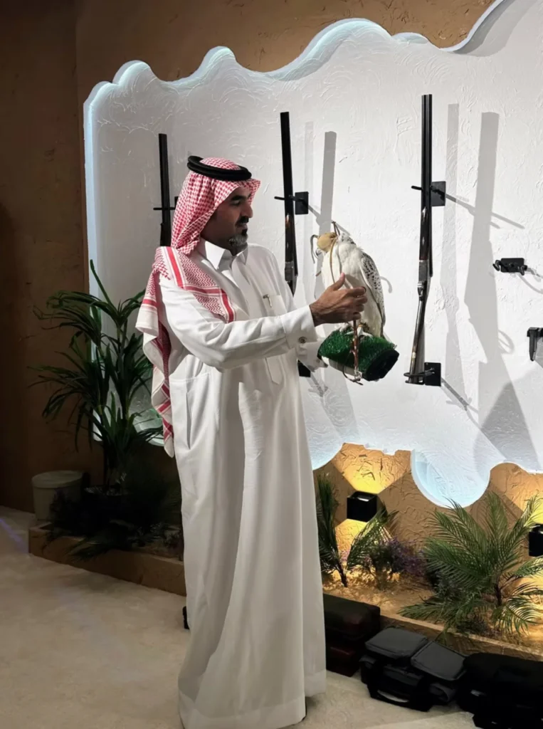 Saudi falconer presenting a hooded white falcon inside the exhibition.