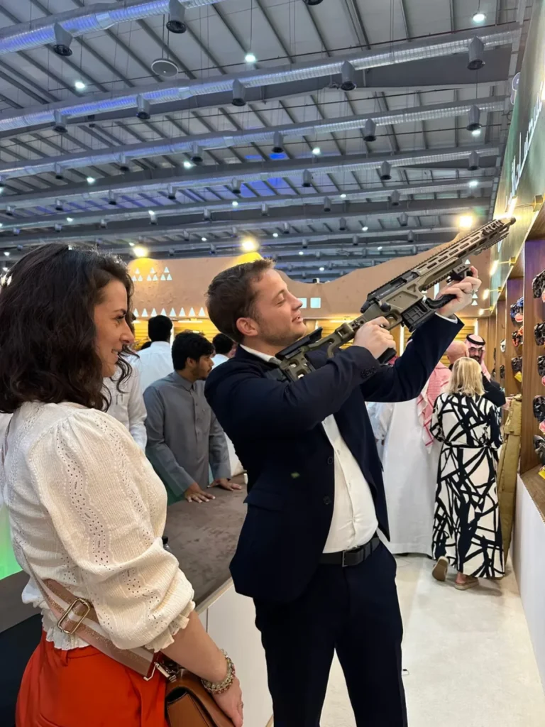 Visitor examining a sporting rifle with guidance from an exhibitor.