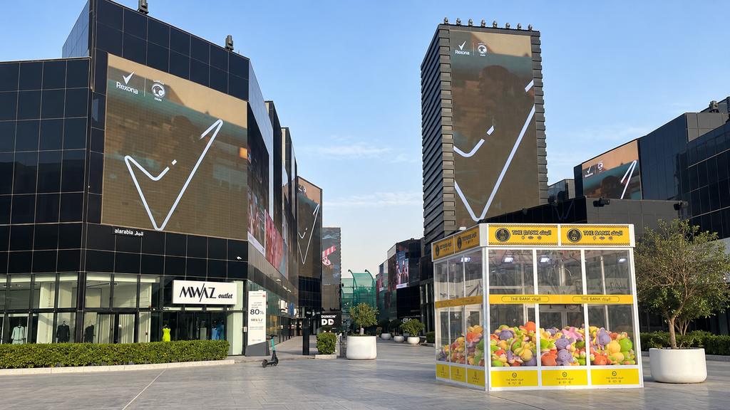 Marketing in Saudi Arabia on large outdoor screens across a modern commercial district.